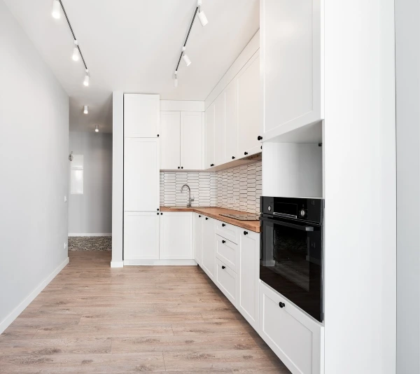 Finished modern kitchen with white cabinets and wooden floor